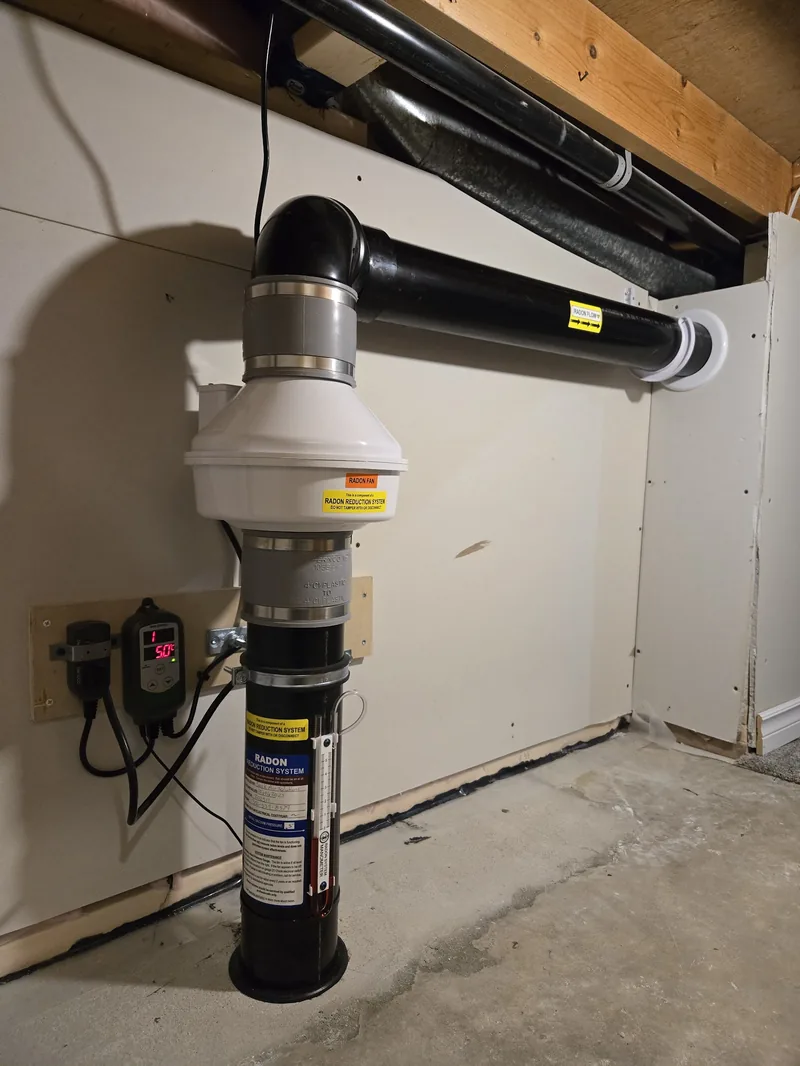 A completed radon mitigation fan and pipe system in a Regina home