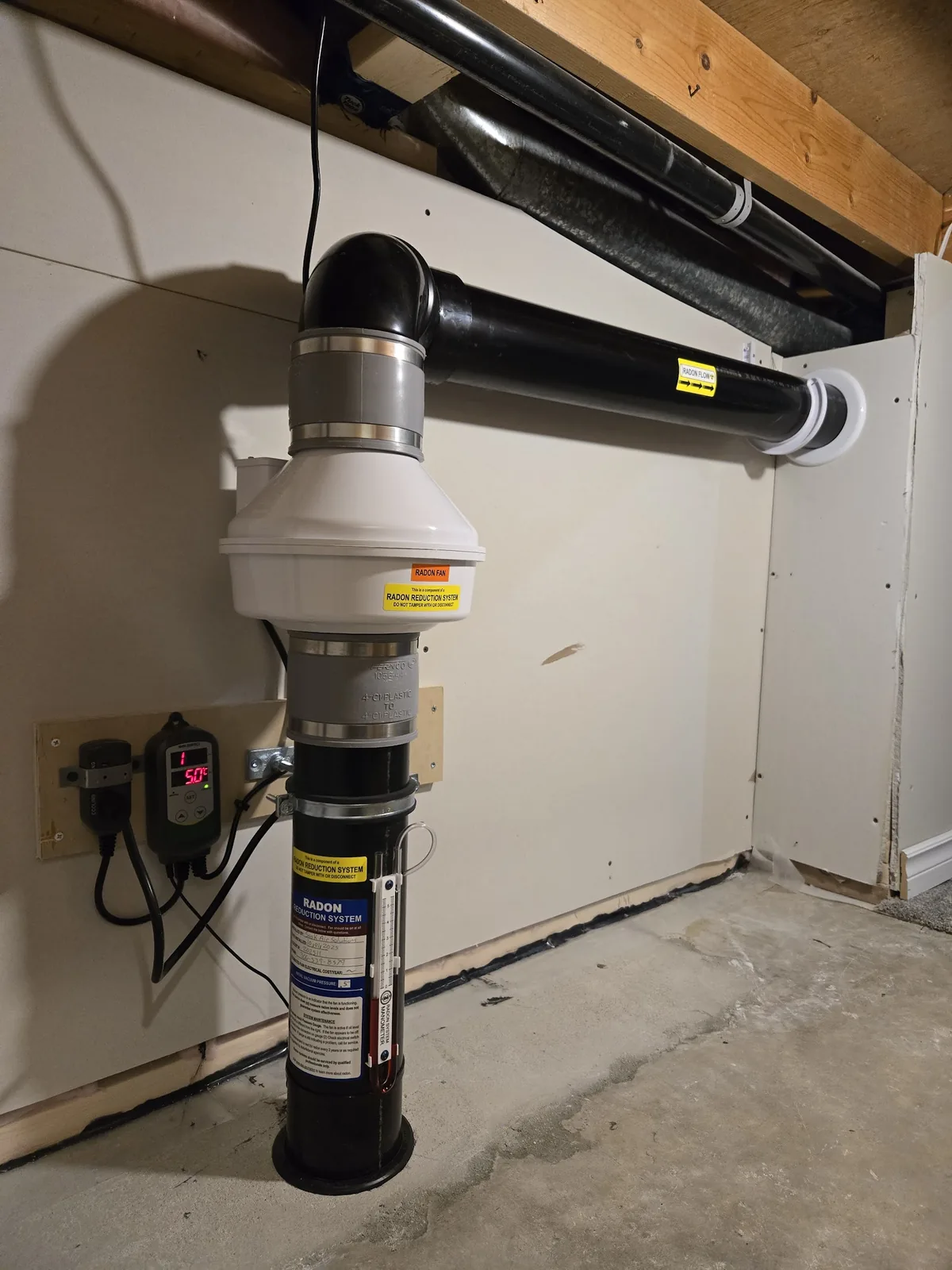 A completed Sask Air radon mitigation system with a neatly routed vent pipe
